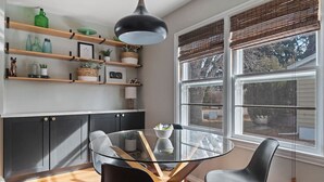 A modern kitchen with a glass dining table, black chairs, and wooden shelves with various items. - Walk to Parks- Pet Friendly-Top Neighborhood (Rapid City)