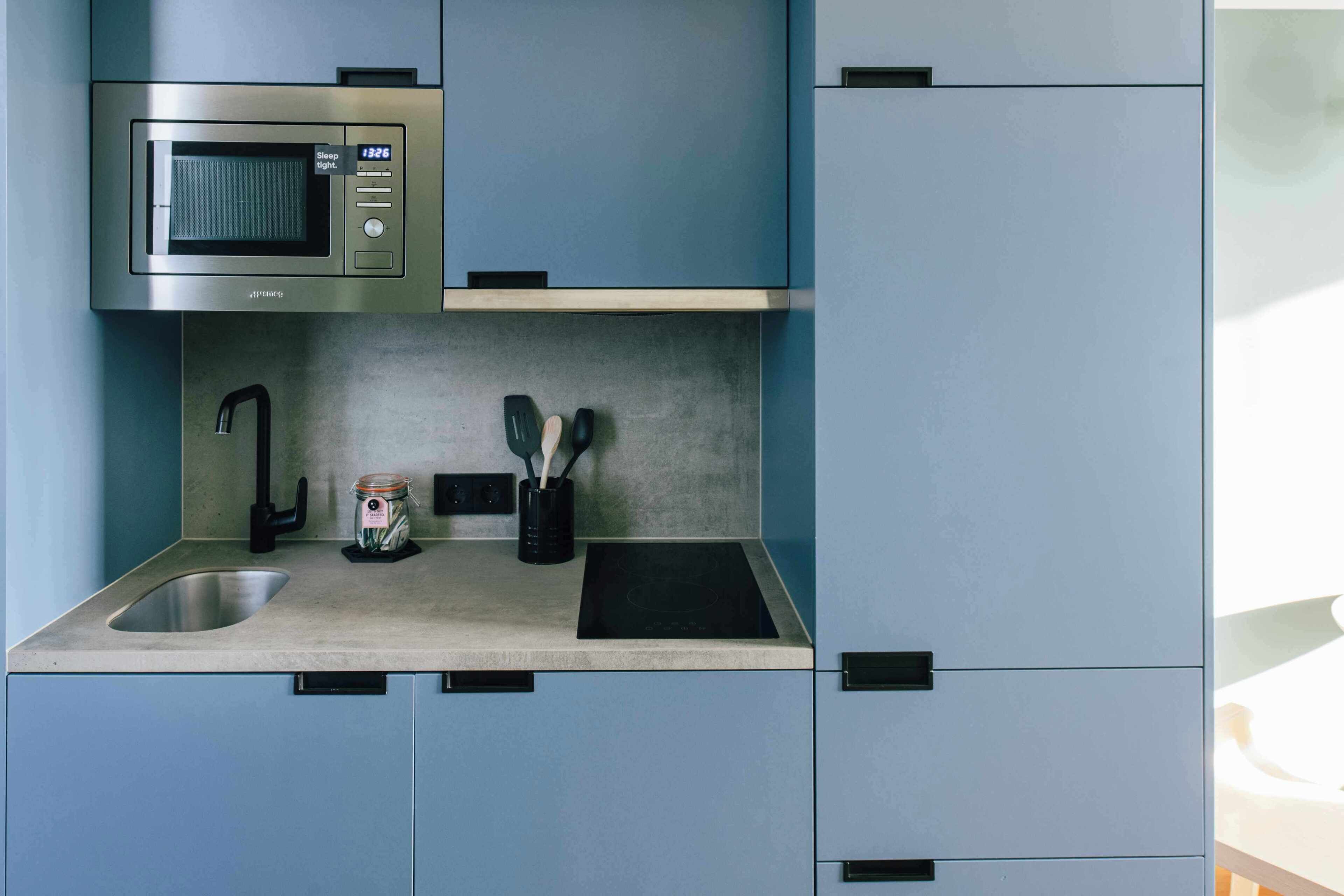 A kitchen with a built-in microwave, a sink, and a countertop with utensils.