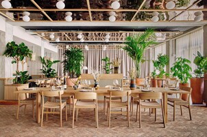 Un ristorante con arredi in legno, piante in vaso e un pavimento con motivo a spina di pesce.