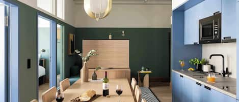 Une cuisine moderne dotée d’un four à micro-ondes encastré, un coin repas avec une table et des chaises en bois, et une vue sur l’espace de vie adjacent.