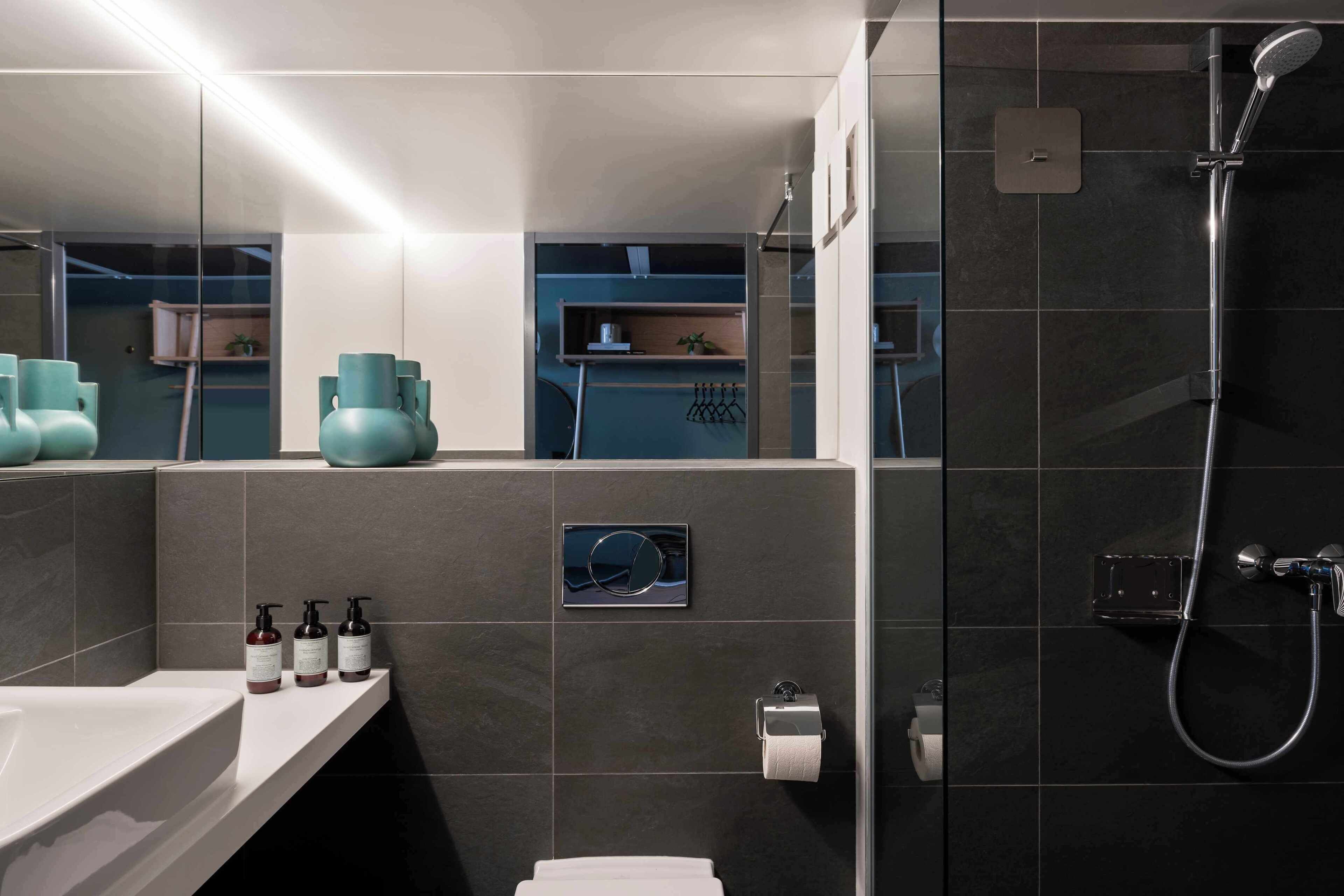 Ein modernes Badezimmer mit Badewanne, Dusche und Toilette. Auf der Ablage liegen Pflegeprodukte und ein Handtuchhalter ist vorhanden.