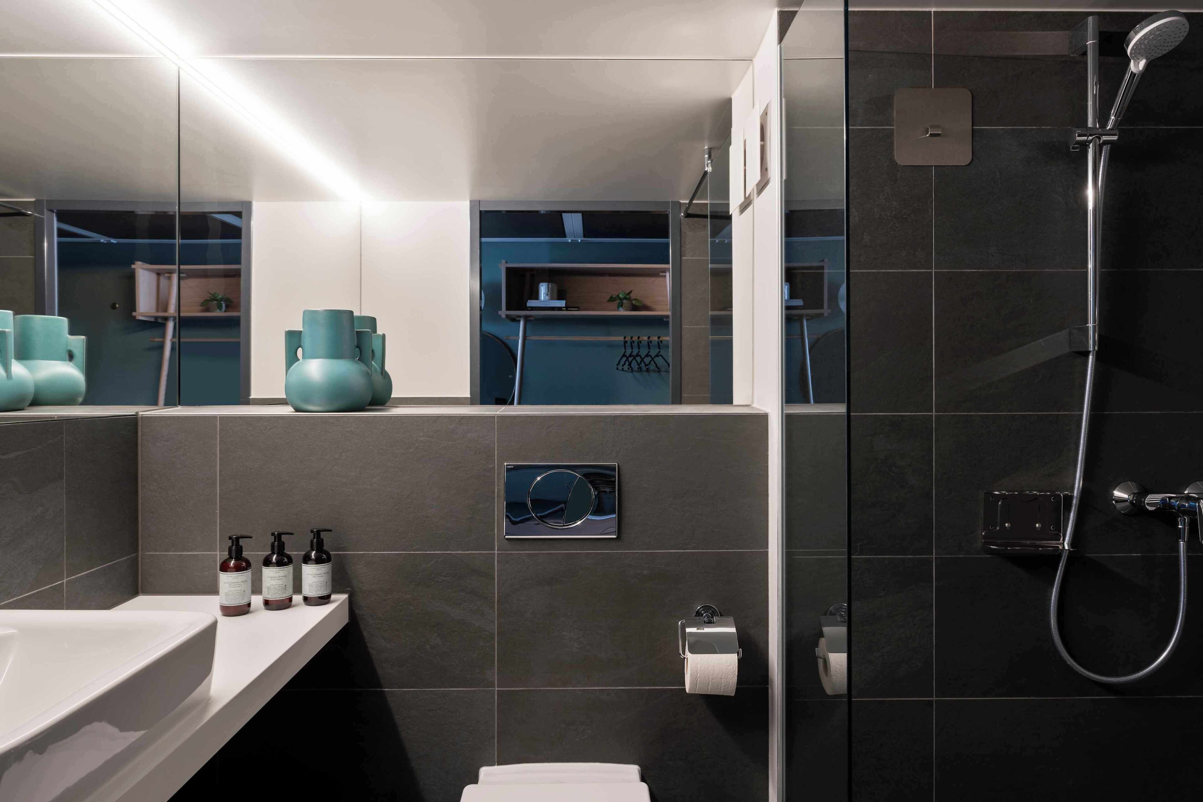 Une salle de bain moderne avec un grand miroir, une douche et un lavabo.