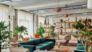 A modern living room with a sectional sofa, armchairs, a coffee table, and a variety of potted plants. - WunderLocke Munich (Munich)