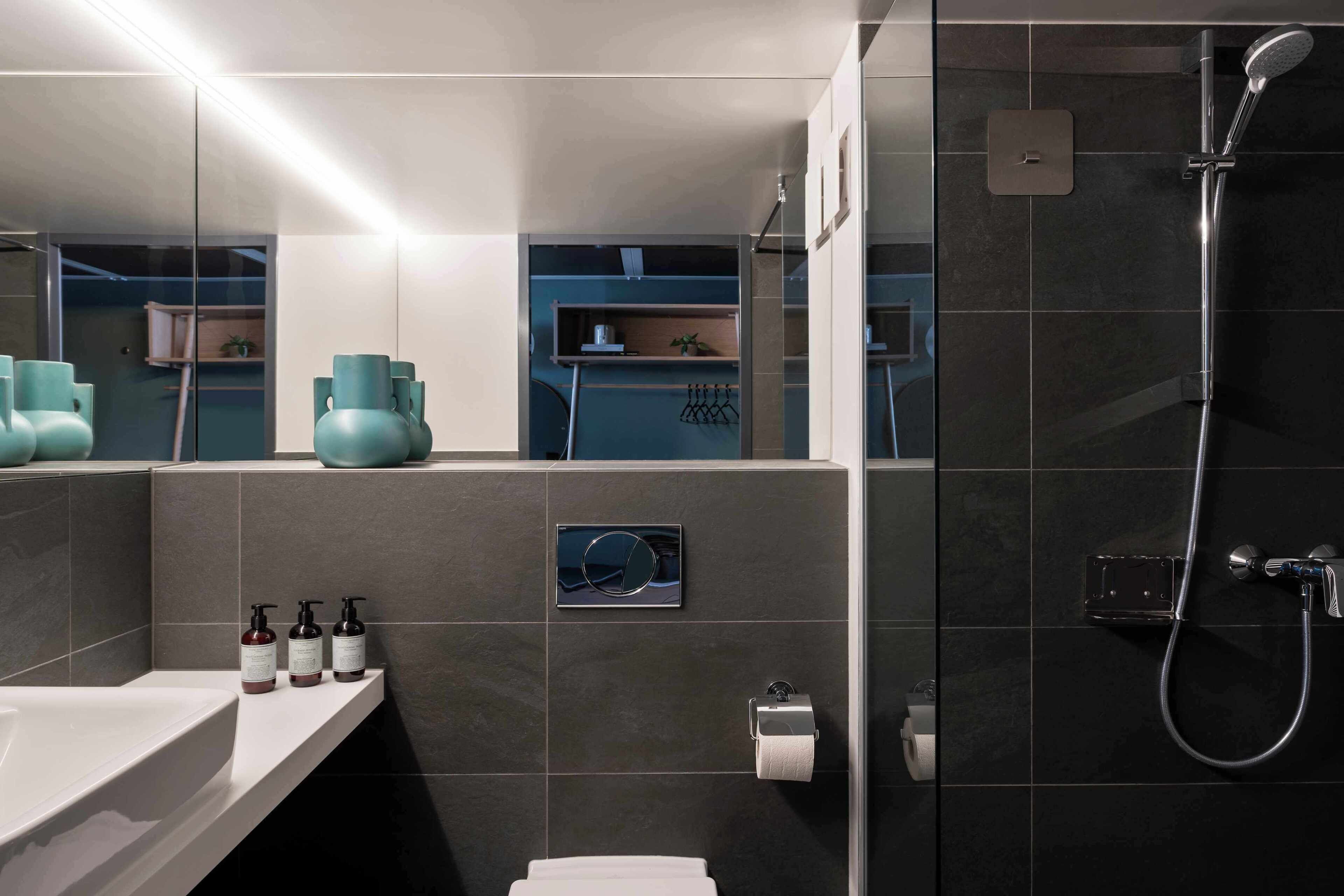 Un baño moderno con ducha, lavamanos y espejo.