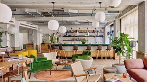 A modern interior with a bar area, seating, and a large plant. - WunderLocke Munich (Munich)