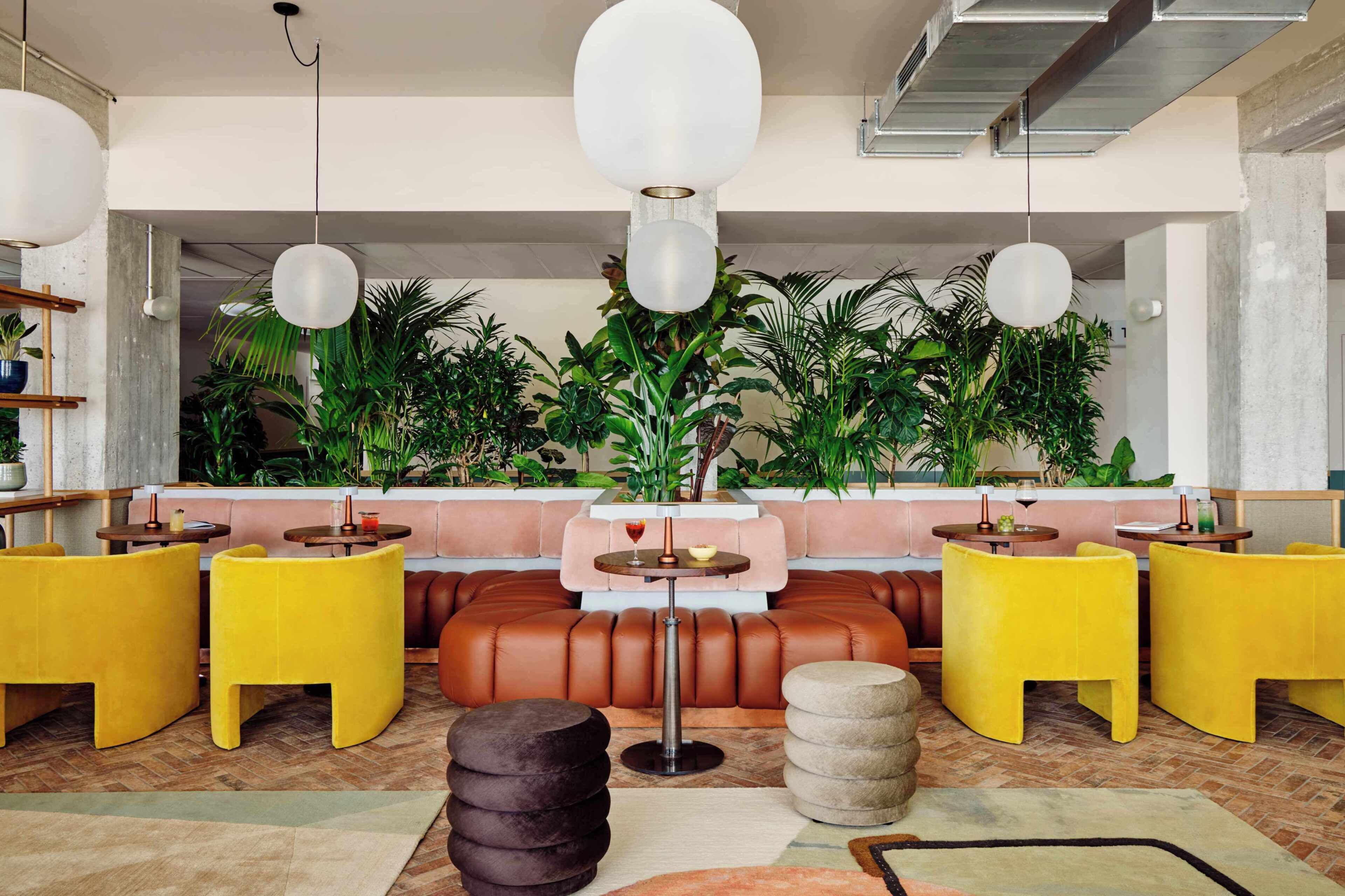 A modern lounge area with leather seating, round tables, and hanging pendant lights.