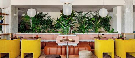 A modern lounge area with leather seating, round tables, and hanging pendant lights.