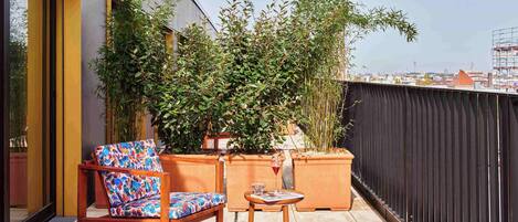 A balcony with a wooden chair, a small table, and potted plants.