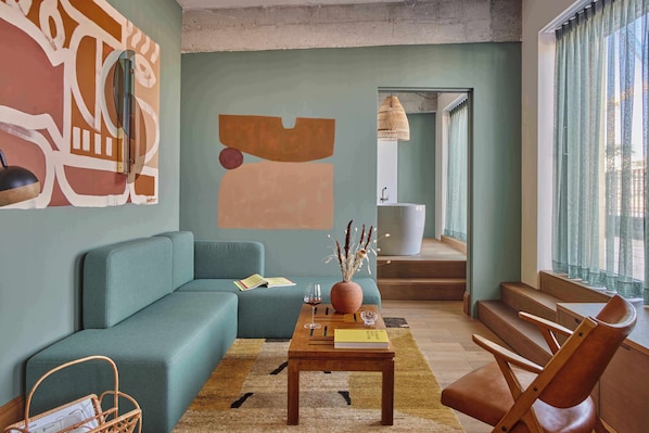 A living room with a sofa, coffee table, and a chair. There is a staircase leading to an upper level. - WunderLocke Munich (Munich)