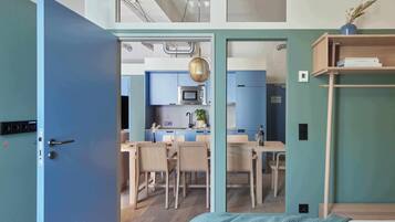 A modern room with a bed, a blue door leading to a kitchen, and a wooden shelf.