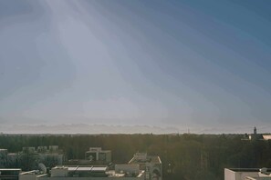 A cityscape with buildings, a clear sky, and distant mountains. - WunderLocke Munich (Munich)