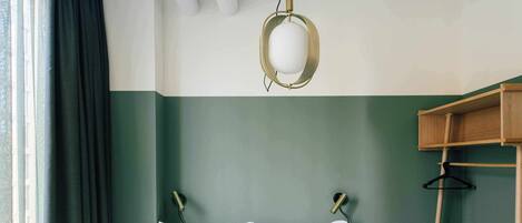 A bed with white bedding, a hanging light fixture, and a wooden bedside table.
