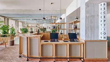 Un mostrador de recepción con computadoras, una barra de madera y un cartel grande que dice 'RECEPTION'.