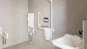 Une salle de bain moderne équipée d’une baignoire, d’une douche avec un pommeau de douche amovible, d’un porte-serviettes et d’un sèche-mains.
