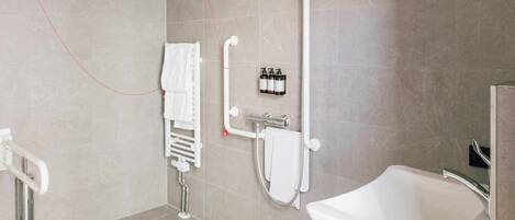 A modern bathroom with a bathtub, a shower with a handheld showerhead, a towel rack, and a hand dryer.