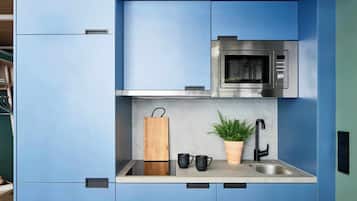 Cocina compacta con microondas, fregadero y una planta en maceta.