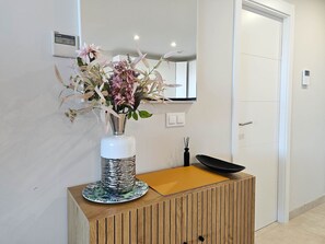 Experience a serene space with a vase holding a beautiful floral arrangement, complemented by a sleek cabinet and modern climate control.