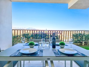 Enjoy a meal with a mountain view from this outdoor dining area, featuring a beautifully set table with wine and greenery.