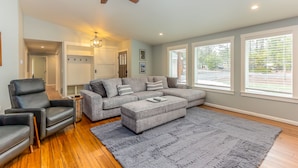 A modern living room with a grey sectional sofa, a black leather chair, a grey ottoman, and a wooden floor. - JACI97-Dog-Friendly Retreat Near Sunriver | Firepit + Fenced Yard (Sunriver)