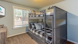 A bunk bed room with a window, a framed sign on the wall, and a small wooden dresser. - JACI97-Dog-Friendly Retreat Near Sunriver | Firepit + Fenced Yard (Sunriver)