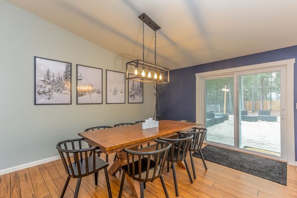 Un comedor con una mesa y sillas de madera, cuadros en la pared y un ventanal con vistas.