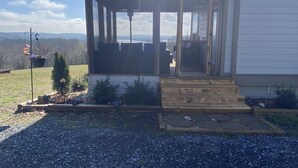 En inglasad veranda med utsikt över en sjö och berg.