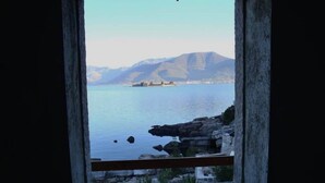 Blick auf die Küste durch ein Fenster mit felsigem Ufer und einer fernen Insel.