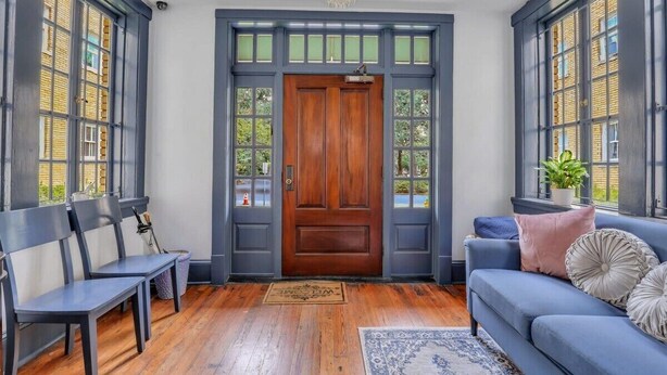 A room with a wooden door, two blue-framed windows, a blue sofa, and a chandelier. - Southern Belle on Oglethorpe Square (Savannah)