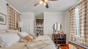 A bedroom with a bed, a ceiling fan, a dresser, a mirror, and a bench. - Southern Belle on Oglethorpe Square (Savannah)
