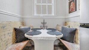A cozy seating area with a round table, cushioned benches, and a window above. - Southern Belle on Oglethorpe Square (Savannah)