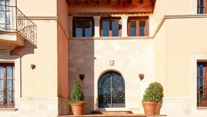 A building with a central entrance, two potted plants, and a tiled staircase leading up to the entrance. - Oliveres - Six Bedroom Villa, Sleeps 12 (Pollença)