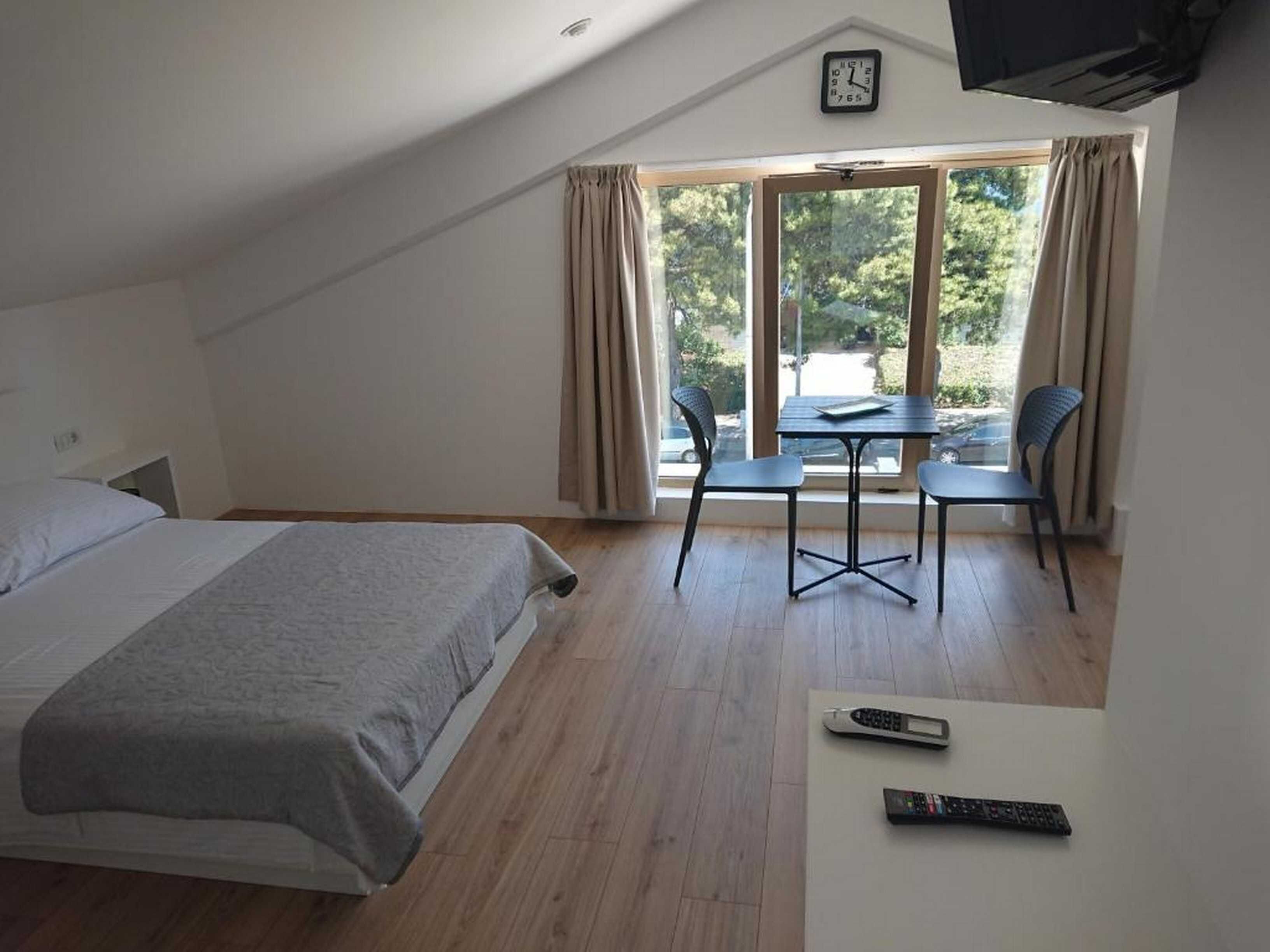 A bedroom with a bed, a desk, two chairs, and a TV.