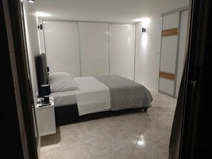 A bedroom with a bed, a bedside table, a wardrobe, and a door. - Apartments Alex (Dubrovnik)