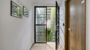 A hallway with a wooden door, a metal gate, and framed pictures on the wall.