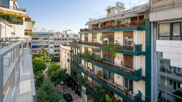 A multi-story building with balconies, some with plants.