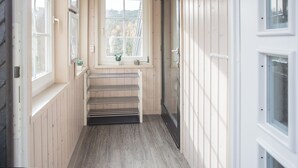 Un corridoio stretto con pareti in legno, una finestra vista alberi e un termosifone.