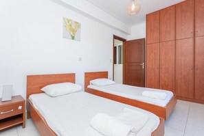 A room with two wooden beds, a nightstand, a wardrobe, and a painting on the wall.