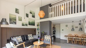 Ein modernes Wohnzimmer mit einer schwarzen Ledersofa, einem runden Couchtisch und einem Essbereich mit Holzsesseln und einem Tisch.