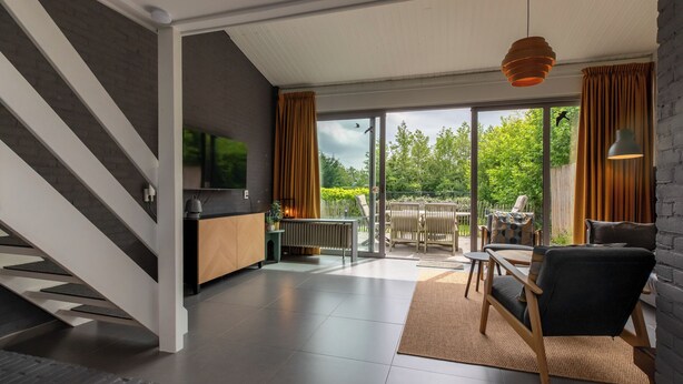 Ein modernes Wohnzimmer mit Fernseher, Sofa und Essbereich.