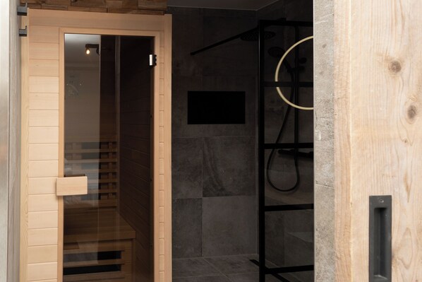 Een moderne badkamer met een douchecabine van glas, een houten deur en een zwarte handdoekhouder.