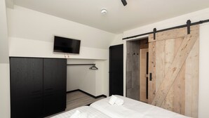 Ett modernt hotellrum med en stor säng, en tv som är monterad på väggen och en skjutdörr i stil med en ladugårdsdörr.