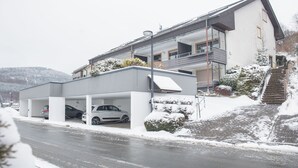 A modern two-story house with a covered carport and a staircase leading to the entrance. - Apt - Am Bergelchen 66-B | Winterberg-Ni (Winterberg)