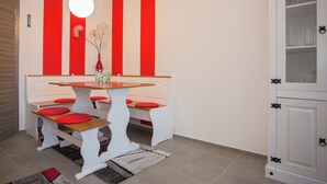A dining area with a white table and benches, red cushions, and a vase with flowers. - Apt - Am Bergelchen 66-B | Winterberg-Ni (Winterberg)