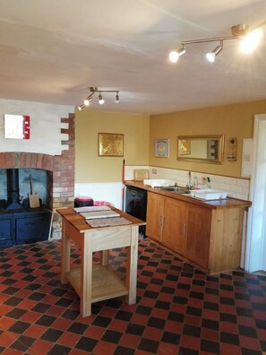 Compact kitchen with central island, vintage-style stove, and checkered tile floor.
