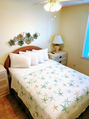 A bedroom with a bed, a nightstand, a lamp, and a wall decoration.