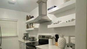 A modern kitchen with white cabinetry, a stainless steel oven, and a coffee maker.