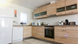 Een moderne keuken met houten kastjes, een ingebouwde oven en een vaatwasser.