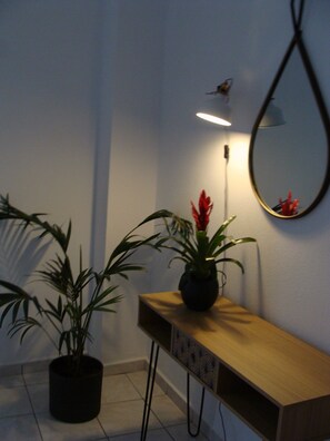 Un coin aménagé avec une console en bois, une plante en pot et un miroir fixé au mur.