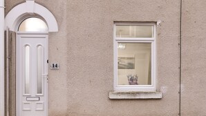 Une maison avec une porte blanche et une fenêtre donnant sur un jardin.