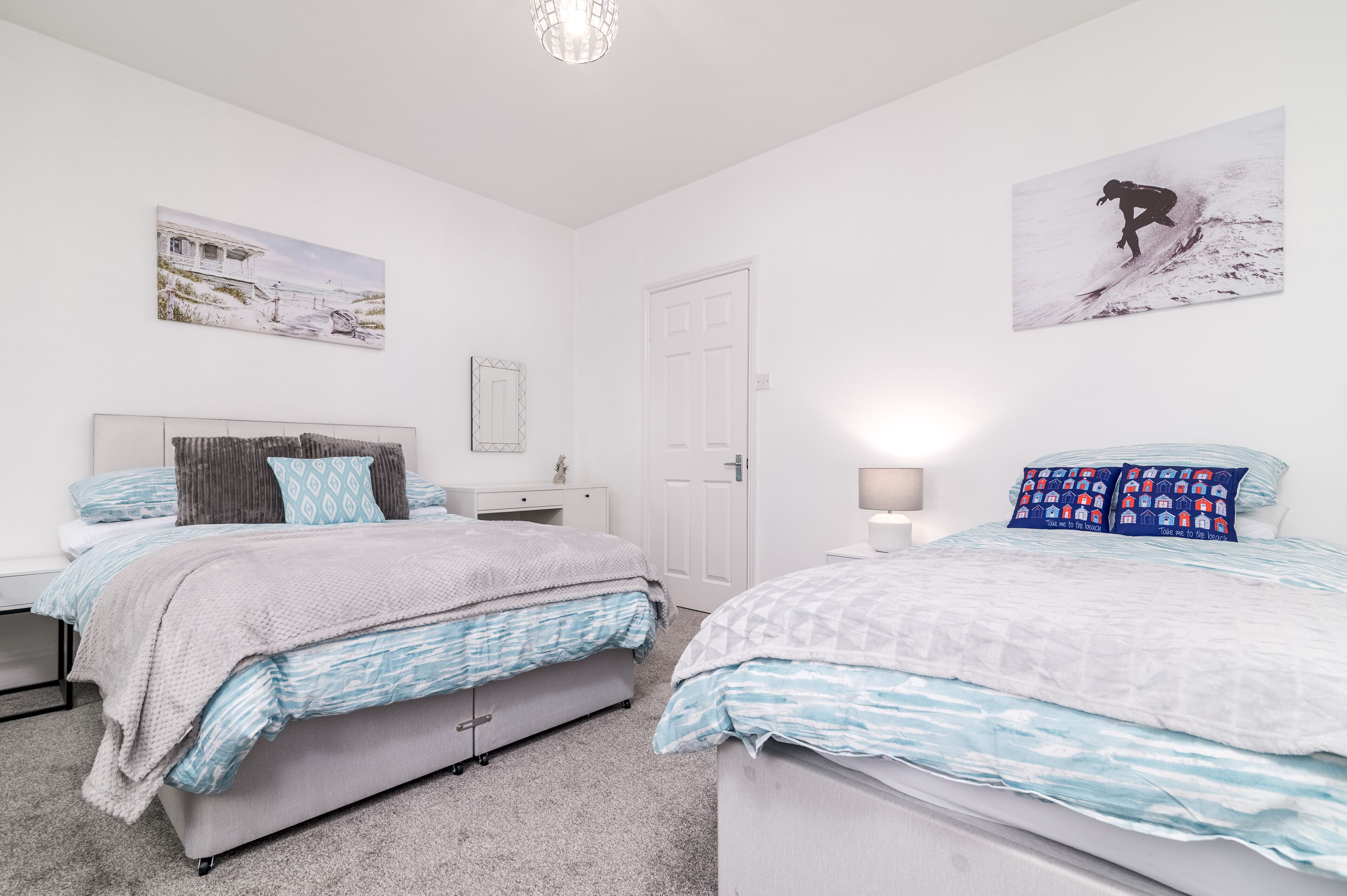 A bedroom with two beds, a dresser, a nightstand, and a mirror.